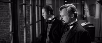 Movie still from “The Elephant Man” (1980), directed by David Lynch – Two men standing next to each other in front of a window; Medium shot, Over the shoulder angle