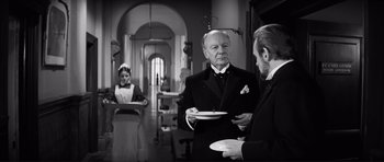 Movie still from “The Elephant Man” (1980), directed by David Lynch – A man and a woman holding plates in a room; Medium shot, Over the shoulder angle