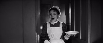 Movie still from “The Elephant Man” (1980), directed by David Lynch – A woman dressed as a maid holding a white plate; Medium shot, High angle