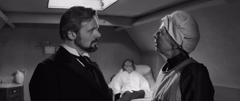 Movie still from “The Elephant Man” (1980), directed by David Lynch – A man and a woman in front of another woman in a room; Medium shot, Over the shoulder angle