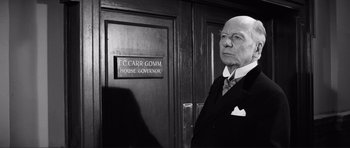 Movie still from “The Elephant Man” (1980), directed by David Lynch – An old man standing in front of a wooden door; Medium shot, Low angle