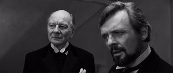 Movie still from “The Elephant Man” (1980), directed by David Lynch – A black and white photo of two men in suits; Close Up shot, Over the shoulder angle