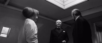 Movie still from “The Elephant Man” (1980), directed by David Lynch – A group of people standing in a room talking to each other; Medium shot, Low angle