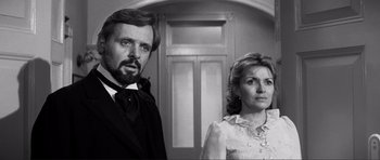 Movie still from “The Elephant Man” (1980), directed by David Lynch – A black and white photo of a man and a woman standing next to each other in front of a door; Close Up shot, Low angle