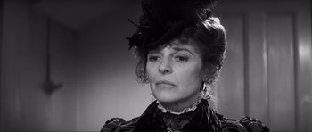 Movie still from “The Elephant Man” (1980), directed by David Lynch – An older woman wearing a black hat and a black dress; Close Up shot, Over the shoulder angle