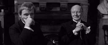 Movie still from “The Elephant Man” (1980), directed by David Lynch – Two men in suits and ties sitting next to each other; Close Up shot, Over the shoulder angle