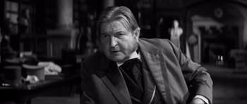 Movie still from “The Elephant Man” (1980), directed by David Lynch – An older man wearing a suit and tie; Close Up shot, Over the shoulder angle