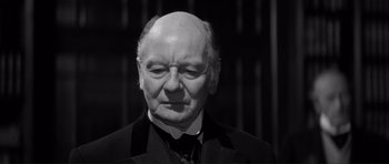 Movie still from “The Elephant Man” (1980), directed by David Lynch – An older man in a suit and tie looking at the camera; Close Up shot, Over the shoulder angle