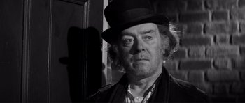 Movie still from “The Elephant Man” (1980), directed by David Lynch – A black and white photo of a man wearing a hat; Close Up shot, Low angle