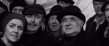 Movie still from “The Elephant Man” (1980), directed by David Lynch – A black and white photo of a group of men wearing hats; Close Up shot, Low angle