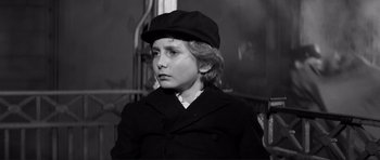 Movie still from “The Elephant Man” (1980), directed by David Lynch – A young boy wearing a black hat and coat; Close Up shot, High angle