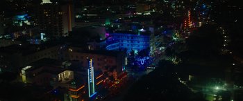 Movie still from “The Enforcer” (2022), directed by Richard Hughes – An aerial view of a city lit up at night; Extreme Wide shot, High angle