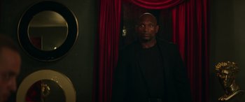 Movie still from “The Enforcer” (2022), directed by Richard Hughes – A man standing in front of a mirror in a dark room; Medium shot, Low angle