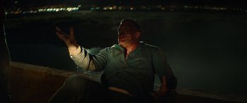 Movie still from “The Enforcer” (2022), directed by Richard Hughes – A man sitting on the ground in the dark; Medium shot, High angle