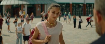 Movie still from “The Enforcer” (2022), directed by Richard Hughes – A woman with a pink bag and a pink backpack; Close Up shot, Over the shoulder angle