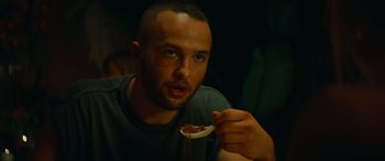 Movie still from “The Enforcer” (2022), directed by Richard Hughes – A man holding a bowl of food in front of his face; Close Up shot, Low angle