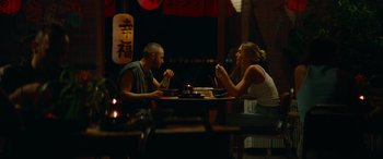 Movie still from “The Enforcer” (2022), directed by Richard Hughes – A man and a woman sitting at a dinner table; Medium shot, Over the shoulder angle