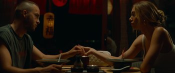 Movie still from “The Enforcer” (2022), directed by Richard Hughes – Two people holding hands over a table with a candle; Medium shot, High angle