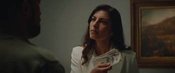 Movie still from “The Enforcer” (2022), directed by Richard Hughes – A woman is holding a stack of money; Close Up shot, Over the shoulder angle