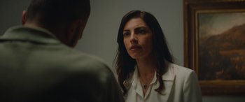 Movie still from “The Enforcer” (2022), directed by Richard Hughes – A woman in a white shirt is looking at a man in a green shirt; Close Up shot, Over the shoulder angle