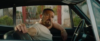 Movie still from “The Enforcer” (2022), directed by Richard Hughes – A man sitting in the back seat of a car; Close Up shot, Over the shoulder angle