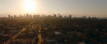Movie still from “The Enforcer” (2022), directed by Richard Hughes – An aerial view of a city with a sun setting in the background; Extreme Wide shot, Low angle