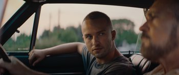 Movie still from “The Enforcer” (2022), directed by Richard Hughes – A person sitting in a car; Close Up shot, Low angle