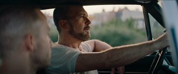 Movie still from “The Enforcer” (2022), directed by Richard Hughes – A man sitting in the driver's seat of a car; Close Up shot, Over the shoulder angle