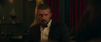 Movie still from “The Enforcer” (2022), directed by Richard Hughes – A person wearing a suit and tie; Close Up shot, Over the shoulder angle