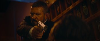 Movie still from “The Enforcer” (2022), directed by Richard Hughes – A man holding a gun while wearing a suit and tie; Close Up shot, Over the shoulder angle