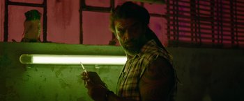 Movie still from “The Enforcer” (2022), directed by Richard Hughes – A man holding a cell phone while standing in a dark room; Close Up shot, Low angle