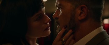 Movie still from “The Enforcer” (2022), directed by Richard Hughes – A man and a woman face to face with one of them touching his face; Close Up shot, Low angle