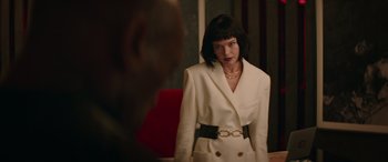 Movie still from “The Enforcer” (2022), directed by Richard Hughes – A woman in a white suit looking into a mirror; Medium shot, Low angle