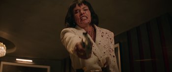 Movie still from “The Enforcer” (2022), directed by Richard Hughes – A woman with blood all over her face holding a gun; Medium shot, Low angle
