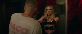 Movie still from “The Enforcer” (2022), directed by Richard Hughes – A woman in a black bra is taking a picture of a man in a black shirt; Medium shot, Over the shoulder angle