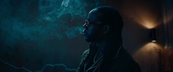 Movie still from “The Enforcer” (2022), directed by Richard Hughes – A man smoking a cigarette in a dark room; Close Up shot, Low angle