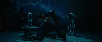 Movie still from “The Enforcer” (2022), directed by Richard Hughes – A man sitting in a chair in front of a wall of lightning; Wide shot, High angle