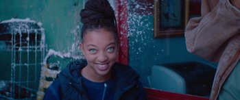 Movie still from “The Enforcer” (2022), directed by Richard Hughes – A young woman with blue eyes smiling for the camera; Close Up shot, Over the shoulder angle