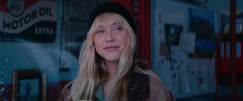 Movie still from “The Enforcer” (2022), directed by Richard Hughes – A woman with long blonde hair wearing a black hat; Close Up shot, Over the shoulder angle
