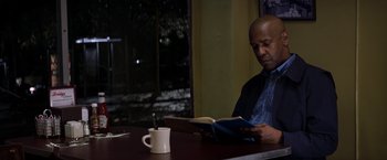 Movie still from “The Equalizer” (2014), directed by Antoine Fuqua – A man sitting at a table reading a book; Medium shot, Low angle