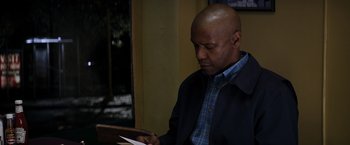 Movie still from “The Equalizer” (2014), directed by Antoine Fuqua – A man looking down at a piece of paper; Medium shot, Over the shoulder angle