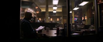 Movie still from “The Equalizer” (2014), directed by Antoine Fuqua – A man sitting at a table in a restaurant reading; Wide shot, Over the shoulder angle