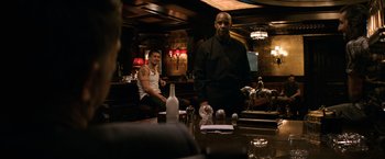 Movie still from “The Equalizer” (2014), directed by Antoine Fuqua – Two men sitting at a table in front of a bar; Medium shot, Over the shoulder angle