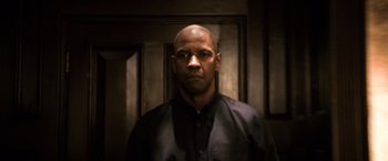 Movie still from “The Equalizer” (2014), directed by Antoine Fuqua – A man in a black shirt is standing in front of a door; Close Up shot, Low angle