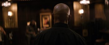 Movie still from “The Equalizer” (2014), directed by Antoine Fuqua – A man with a bald head is standing in front of a painting; Close Up shot, Over the shoulder angle