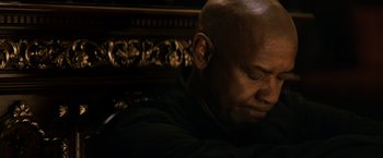 Movie still from “The Equalizer” (2014), directed by Antoine Fuqua – A man sitting in front of an ornate wooden bench; Close Up shot, High angle