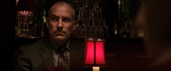 Movie still from “The Equalizer” (2014), directed by Antoine Fuqua – A man in a suit sitting in front of a lamp; Close Up shot, Low angle