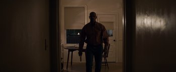 Movie still from “The Equalizer” (2014), directed by Antoine Fuqua – A man standing in a living room holding a knife; Medium shot, Low angle