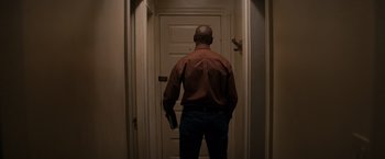 Movie still from “The Equalizer” (2014), directed by Antoine Fuqua – A man holding a gun standing in front of an open door; Medium shot, Low angle