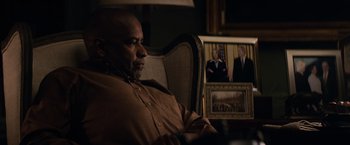 Movie still from “The Equalizer” (2014), directed by Antoine Fuqua – A man sitting in a chair in front of a picture; Medium shot, Over the shoulder angle